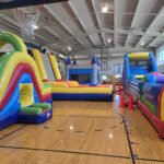 Colorful indoor inflatable obstacle courses set up in gym – Omaha bounce house delivery by Jumpers4You