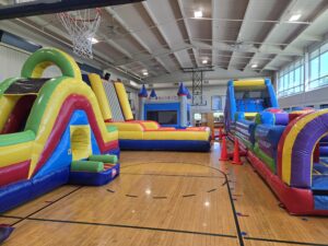 Colorful indoor inflatable obstacle courses set up in gym – Omaha bounce house delivery by Jumpers4You