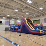 Massive inflatable obstacle course with slide set up in Omaha gym – Omaha bounce house delivery by Jumpers4You