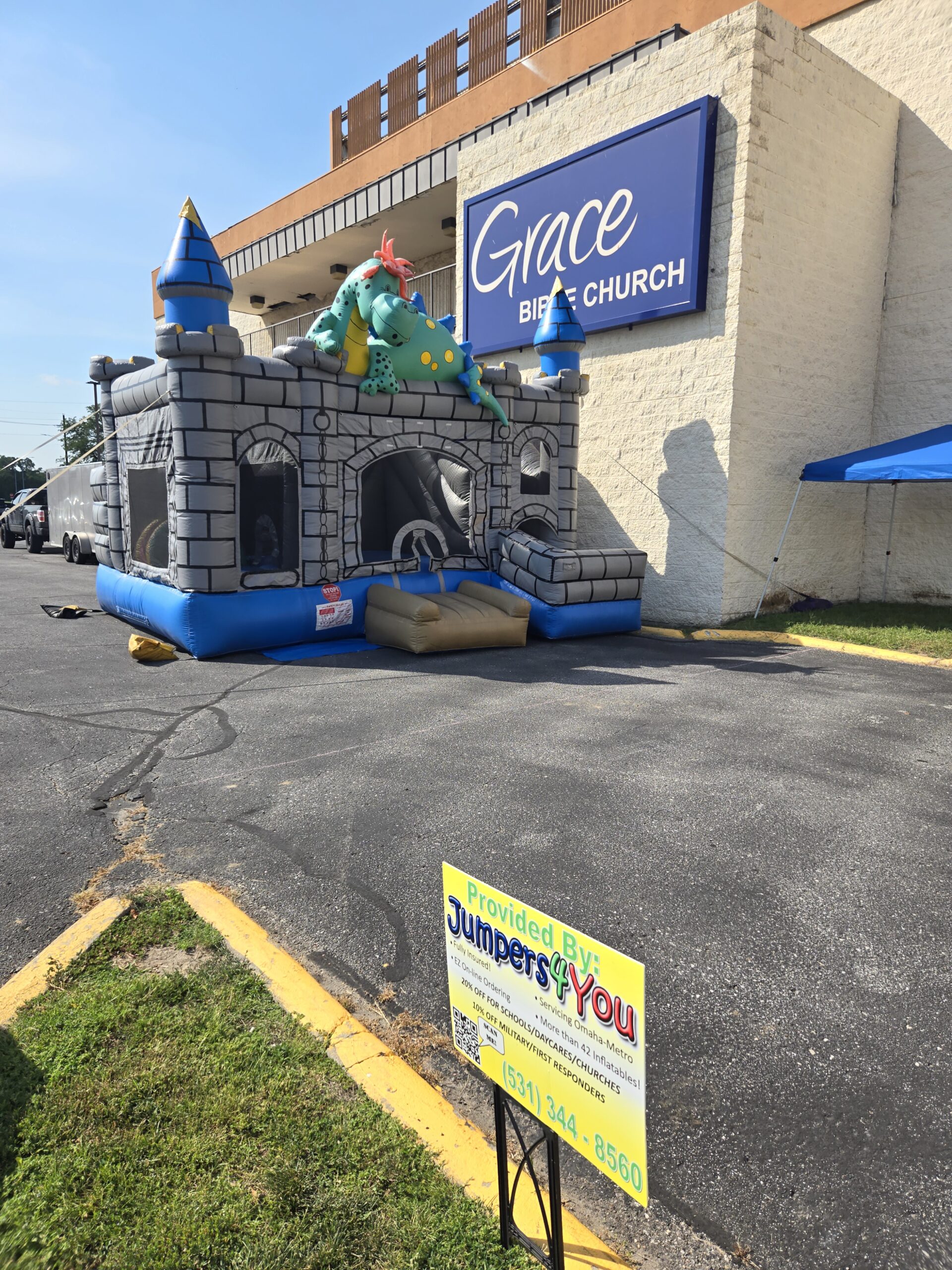 Gray dragon castle bounce house with a Jumpers4You sign near the entrance